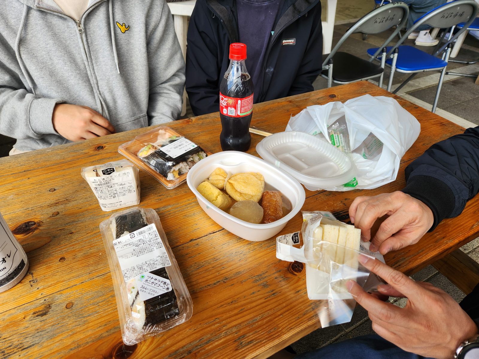 나무 테이블 위에 놓인 삼각김밥과 오뎅, 샌드위치, 음료