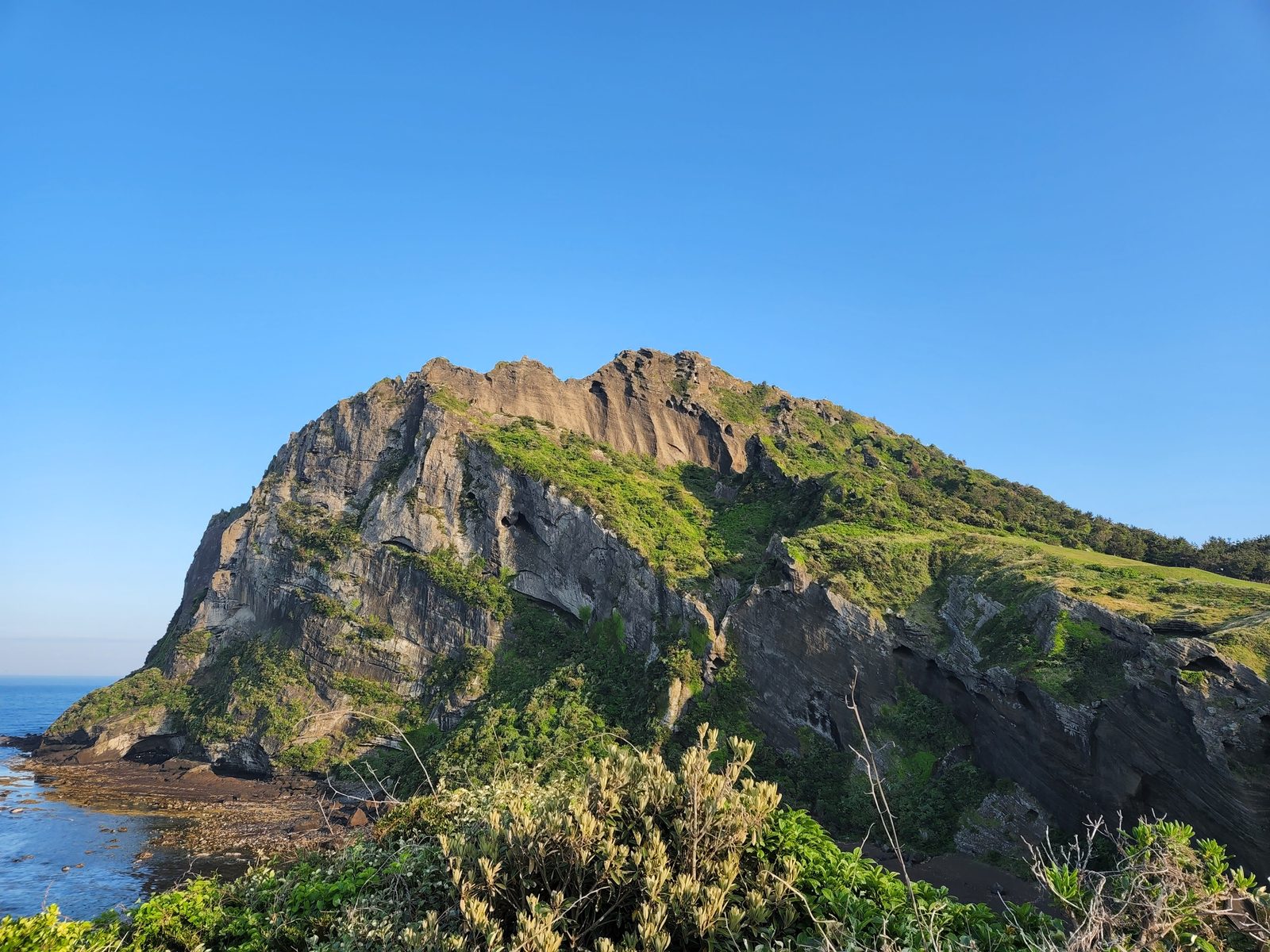 저녁 빛을 받은 성산일출봉의 절벽과 바다