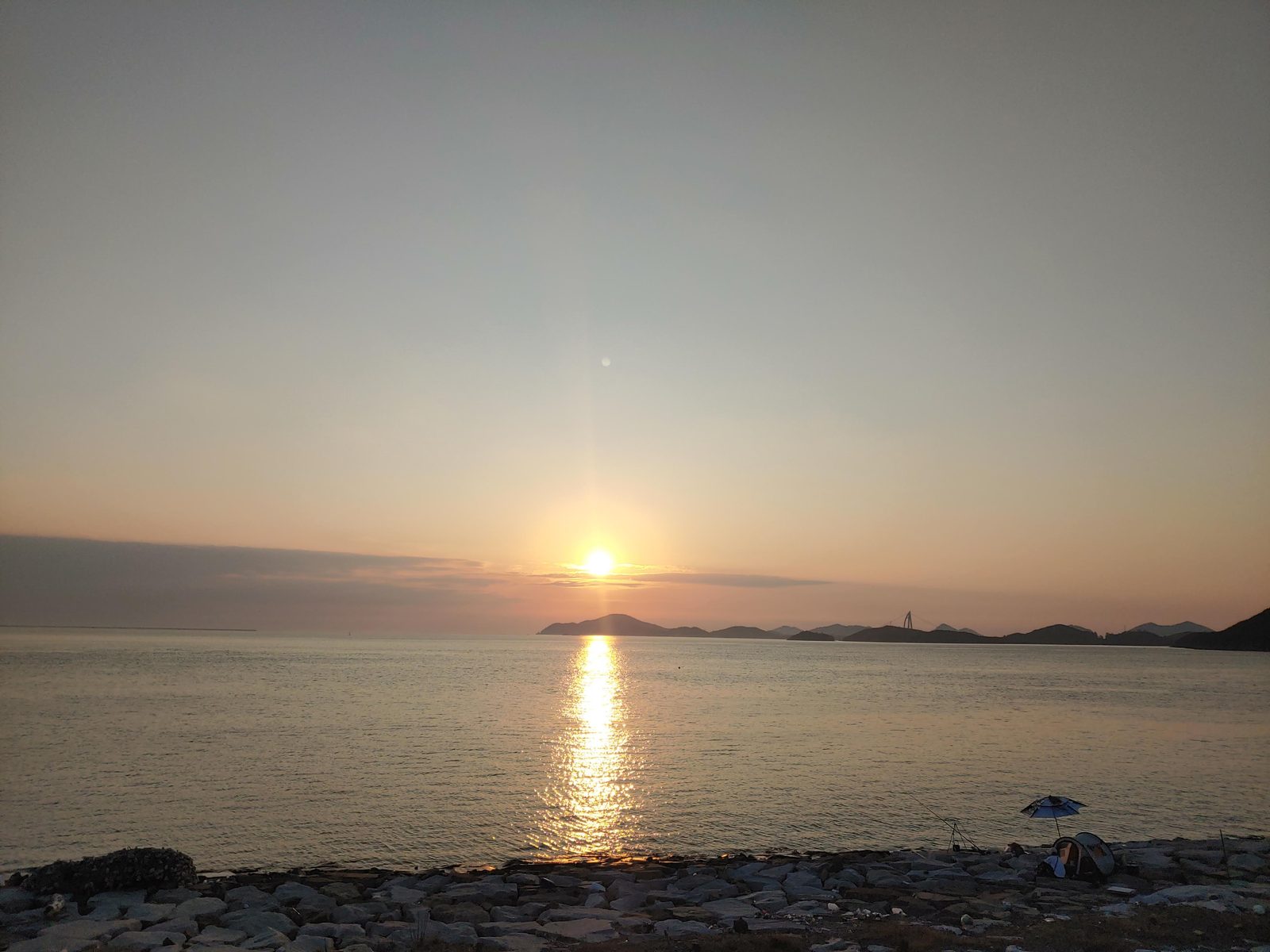 새만금방조제에서 본 낮은 해와 바다 위 긴 반사광