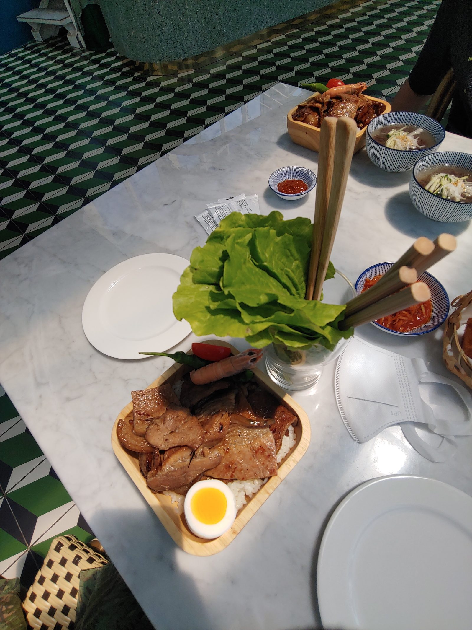 밥 위에 올린 구운 고기와 상추, 반찬이 놓인 식탁